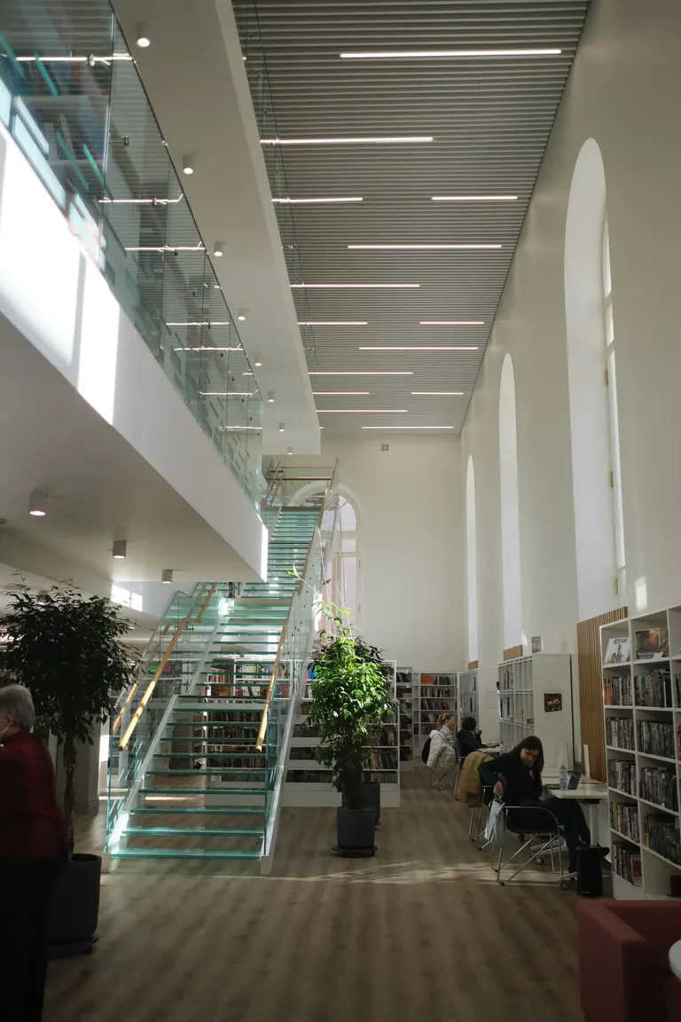 Public library interior with a glass staircase and bookshelves