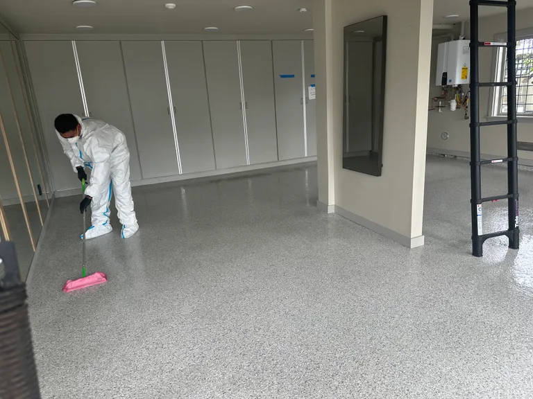 Technician cleaning garage floor in protective suit